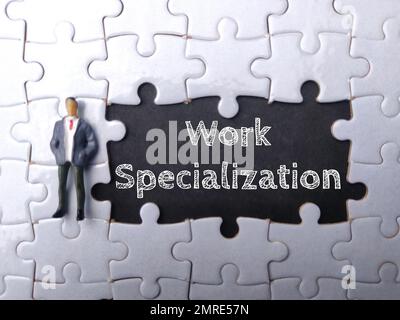 Persone in miniatura e puzzle bianco con la parola specializzazione lavoro Foto Stock