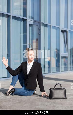 giovane donna piuttosto lavoratore di ufficio pratica yoga asana per la salute spin dopo le ore di lavoro al computer al di fuori del luogo di lavoro in estate giorno di sole Foto Stock