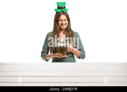 Bella giovane donna con birra vicino al tavolo su sfondo bianco. St Festa di Patrizio Foto Stock