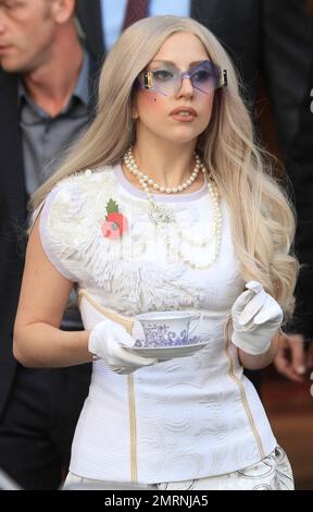 Il megastar Lady Gaga, molto simile a una signora, lascia il suo hotel londinese in un abito a motivi bianchi, in una collana di perle, occhiali da sole esagonali e abbinato a guanti bianchi mentre tiene un tè e un piattino. Gaga mostra rispetto sulla Domenica della memoria indossando un papavero sul petto. Il 25-year-old dovrebbe prendere il posto sull'odierno 'X Factor' live results show. Londra, Regno Unito. 13th novembre 2011. Foto Stock