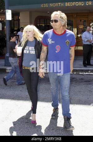 Il batterista Velvet Revolver, precedentemente di Guns and Roses e The Cult, Matt Sorum mostra un po' del suo lato 'cheekier' mentre lega la sua scarpa sul marciapiede mentre fuori e intorno con la ragazza Ace Harper a Beverly Hills, CA. 5/4/10. Foto Stock