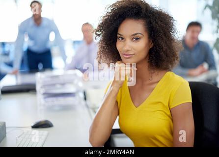 Talento e sicurezza. Ritratto di una giovane donna d'affari attraente con i suoi colleghi sullo sfondo. Foto Stock