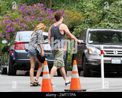 ESCLUSIVO!! Miley Cyrus e il ragazzo dell'attore australiano Liam Hemsworth fare un giro in città in una vettura sportiva cabriolet guidata da Liam prima di fermarsi in un centro dedicato alla meditazione. La coppia lovey-dovey ha speso 30 minuti all'interno prima di camminare fuori del braccio nel braccio e di tenere le mani. Miley, indossando pantaloncini jean e un top basso, baciò teneramente il braccio di Liam prima di rientrare in auto e di zoomare il giorno dei premi Teen Choice. Los Angeles, CA 7th agosto 2011 Foto Stock