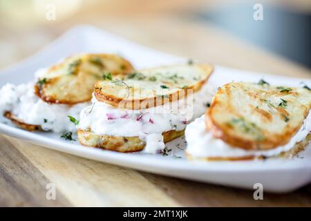Un primo piano di sandwich di patate fatto di due fette di patate e caricato con yogurt greco Foto Stock