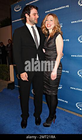 In uno snellente abito da cocktail nero Chelsea Clinton travi come lei tiene le mani con il marito Marc Mezvinsky sul tappeto blu durante Millennium Network Event ospitato dall'ex presidente degli Stati Uniti Bill Clinton tenuto al Boulevard 3. Los Angeles, California. 03/17/11. Foto Stock