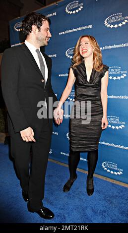 In uno snellente abito da cocktail nero Chelsea Clinton travi come lei tiene le mani con il marito Marc Mezvinsky sul tappeto blu durante Millennium Network Event ospitato dall'ex presidente degli Stati Uniti Bill Clinton tenuto al Boulevard 3. Los Angeles, California. 03/17/11. Foto Stock