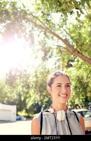 Sentirsi ringiovaniti dopo un ottimo allenamento. una giovane donna sportiva che cammina fuori in una giornata di sole. Foto Stock