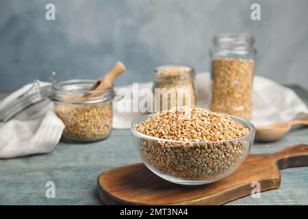 Grano saraceno verde crudo in ciotola su tavola di legno azzurro Foto Stock