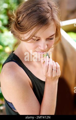 Prendetevi del tempo per odorare le erbe. Una giovane donna che odora le erbe nel suo giardino. Foto Stock