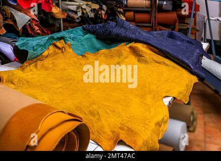 Pelli colorate su un tavolo da lavoro sul retro di una tradizionale bottega e studio artigianale di pelletteria a Centro storico, Firenze, Italia Foto Stock