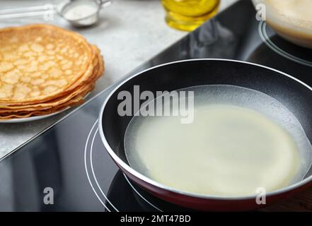 Deliziosa frittella sottile in padella su stufa a induzione, primo piano Foto Stock