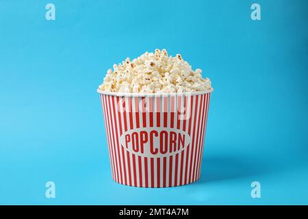 Delizioso popcorn in secchio di carta su sfondo azzurro Foto Stock