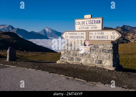 Cartello sul col de l'Iseran 2770 m, il passo lastricato più alto delle Alpi, montagne e creste delle Alpi Graiane in lontananza. Foto Stock