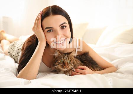 Bella giovane donna con il suo gatto carino a letto. Animale domestico soffice Foto Stock