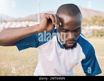 L'uomo nero è stanco, il volto e il giocatore di calcio sul campo all'aperto, giocando a gioco o allenandosi di calcio con energia e l'atleta esausto. Sport di squadra, sudorazione Foto Stock