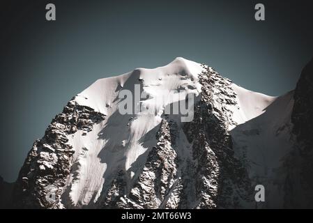 Panorama della lingua di un ghiacciaio alpino con neve discende da alte scogliere rocciose tra le cime dell'Altai all'ombra. Top racconto fairy. Foto Stock