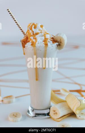 Un colpo verticale di un milkshake di caramello fresco con banana isolato su fondo bianco vuoto Foto Stock