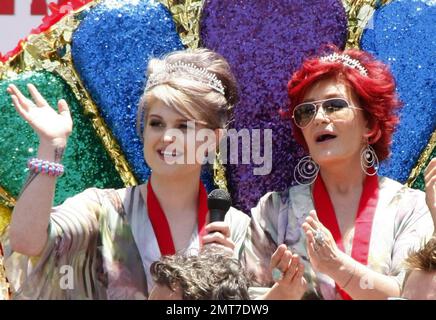 I Grand Marshals Sharon e Kelly Osbourne navigano lungo il Santa Monica Boulevard su un galleggiante dai colori brillanti con arcobaleno ornato da paillettes e abiti coordinati durante la sfilata annuale di Los Angeles Gay Pride 40th. Secondo i rapporti le stelle della TV di realtà sono state confrontate dai manifestanti anti anti-gay, ma il duo madre-figlia è stato inalterato e continuato sopra. Kelly, che ha anche mostrato la sua scissione e goduto di un lollipop, in seguito firmato autografi e Sharon abbracciato un fan. Si stima che 400, 000 persone siano state presenti all'evento ad alta energia. Los Angeles, California. 06/13/10. . Foto Stock