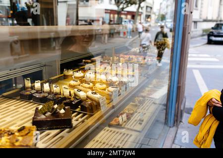 Riflessione in vetro di donna anziana guardando la vetrina di una pasticceria boulangerie scelta di un dolce dessert Foto Stock