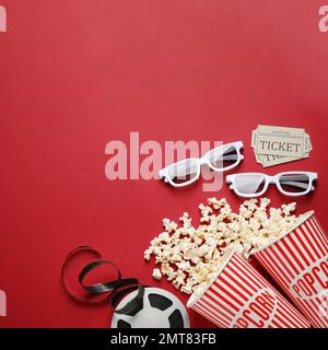 Composizione piatta con delizioso popcorn su sfondo rosso Foto Stock