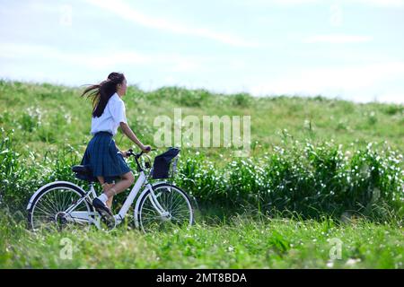 Studente di scuola superiore giapponese in bicicletta all'aperto Foto Stock