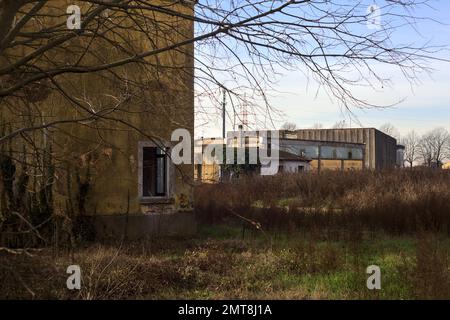 Complesso industriale abbandonato chiuso da un cancello nella campagna italiana Foto Stock