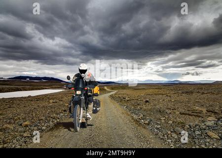 Un uomo motociclista che guida su una strada di ghiaia nel deserto di Kaldidalur. Moto Avventura in Islanda. Foto Stock