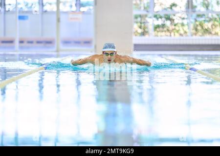 Atleta giapponese che nuota nella piscina coperta Foto Stock