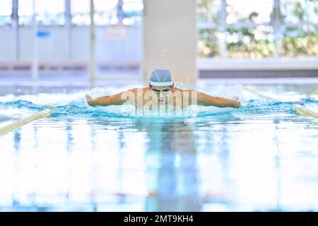 Atleta giapponese che nuota nella piscina coperta Foto Stock