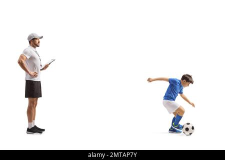 Profilo a tutta lunghezza di un allenatore di calcio che guarda un ragazzo allenarsi con una palla isolata su sfondo bianco Foto Stock