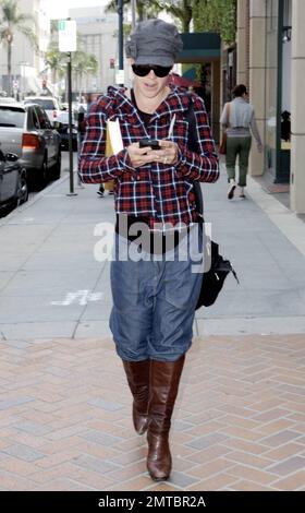 La cantante Pink tiene la testa mentre parla mentre passeggiando a Beverly Hills, ma ha guardato brevemente per verificare i suoi dintorni. Portando un libro sotto un braccio, Pink indossava una giacca a plaid con jeans baggy e stivali marroni al ginocchio. Beverly Hills, California. 3/24/10. . Foto Stock