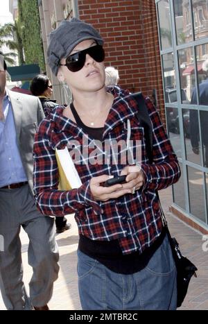 La cantante Pink tiene la testa mentre parla mentre passeggiando a Beverly Hills, ma ha guardato brevemente per verificare i suoi dintorni. Portando un libro sotto un braccio, Pink indossava una giacca a plaid con jeans baggy e stivali marroni al ginocchio. Beverly Hills, California. 3/24/10. . Foto Stock