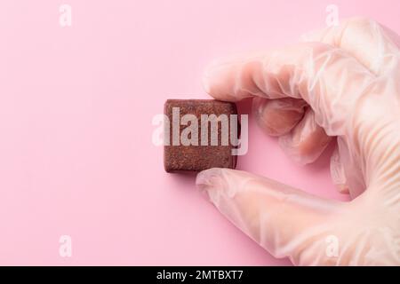 Bonbon al cioccolato dipinto a mano in mano umana. Delizioso dessert su sfondo rosa con copyspace Foto Stock