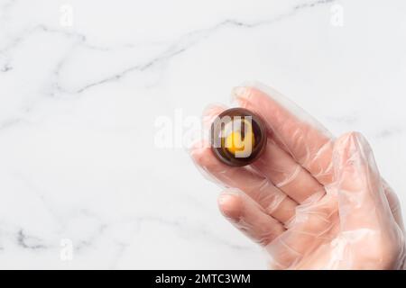 Bonbon al cioccolato dipinto a mano in mano umana. Delizioso dessert su sfondo bianco con copyspace Foto Stock
