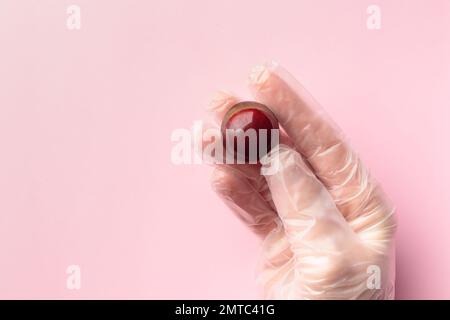 Bonbon al cioccolato dipinto a mano in mano umana. Delizioso dessert su sfondo rosa con copyspace Foto Stock