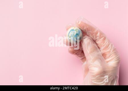 Bonbon al cioccolato dipinto a mano in mano umana. Delizioso dessert su sfondo rosa con copyspace Foto Stock