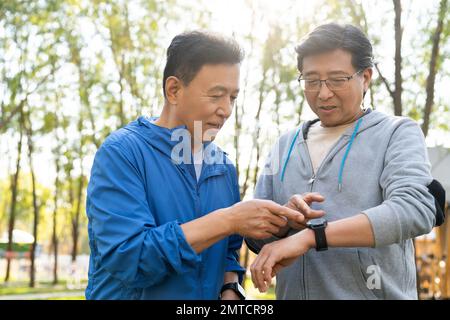 I due movimenti degli uomini più anziani guardano l'orologio sportivo Foto Stock