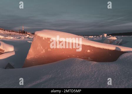 Un pezzo di ghiaccio esce dalla neve sul fiume Vilyui a Yakutia sullo sfondo della torre radiofonica nel villaggio di suntar. Foto Stock