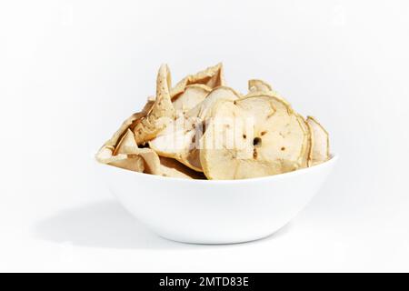 Patatine di mela asciutte in un piatto bianco isolato su uno sfondo bianco. Cibo disidratato. Un mazzo di patatine di mela. Dieta sana dello spuntino. Foto Stock