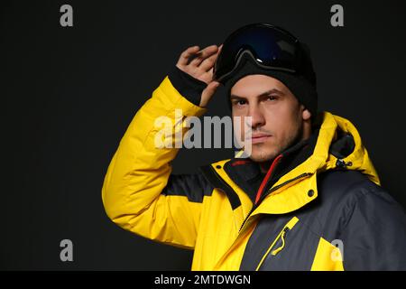 Uomo che indossa abiti sportivi invernali su sfondo nero Foto Stock