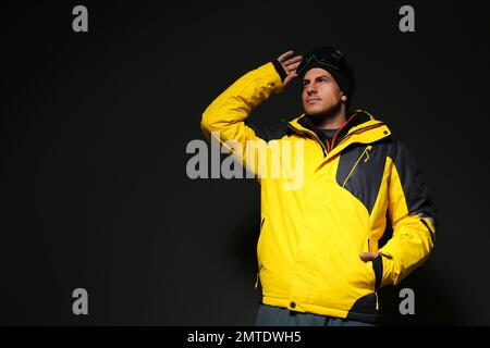 Uomo che indossa abiti sportivi invernali su sfondo nero Foto Stock