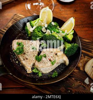 Schweinesteak / Brokkoli / Broccoli mit Zitrone und Petersilie in der Pfanne Foto Stock