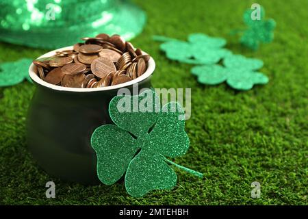 Pentola di monete d'oro e trifoglio su erba verde, primo piano. St Festa di Patrizio Foto Stock