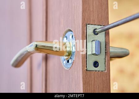 Riparazione della maniglia della porta a leva con dispositivo di chiusura su una porta interna. Foto Stock