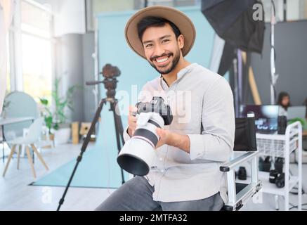 Ritratto, fotografo e uomo con fotocamera in studio, felice e sorridere prima di una foto. Viso, fotografia e ragazzo asiatico rilassarsi durante il lavoro Foto Stock