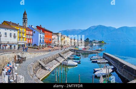 Storiche case colorate in Piazza Giuseppe Motta, di fronte al Lago maggiore con piccole barche nel porto di Ascona, Svizzera Foto Stock