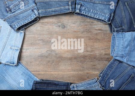 Cornice in jeans eleganti su sfondo in legno, piano. Spazio per il testo Foto Stock