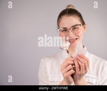 Medico estetista che tiene gouache raschietto e rullo. Foto Stock