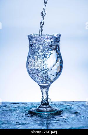 L'immagine di versare acqua potabile, in un vetro rotto, che fa sentire rinfrescato su sfondo bianco sfocato, spruzzi d'acqua, acqua frizzante, Foto Stock