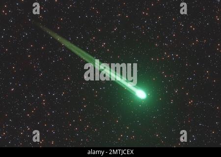 Cometa verde con un sentiero luminoso che vola attraverso il cielo su sfondo stellato. Illustrazione del concetto di astronomia e meteore Foto Stock